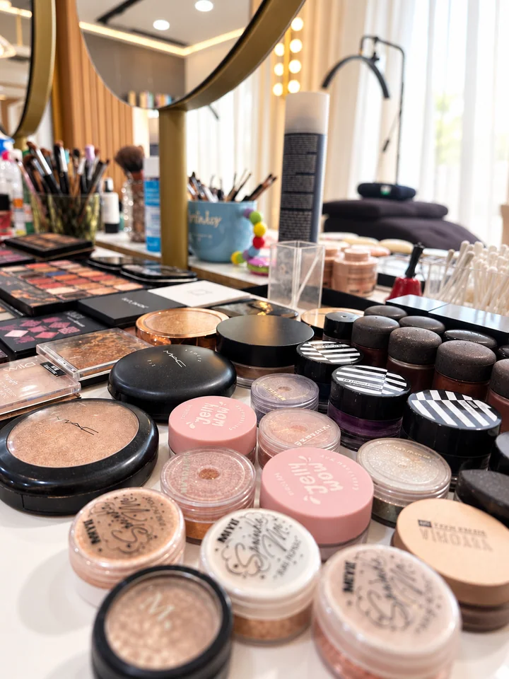 The actual makeup palettes, powders and brushes arranged on the salon counter